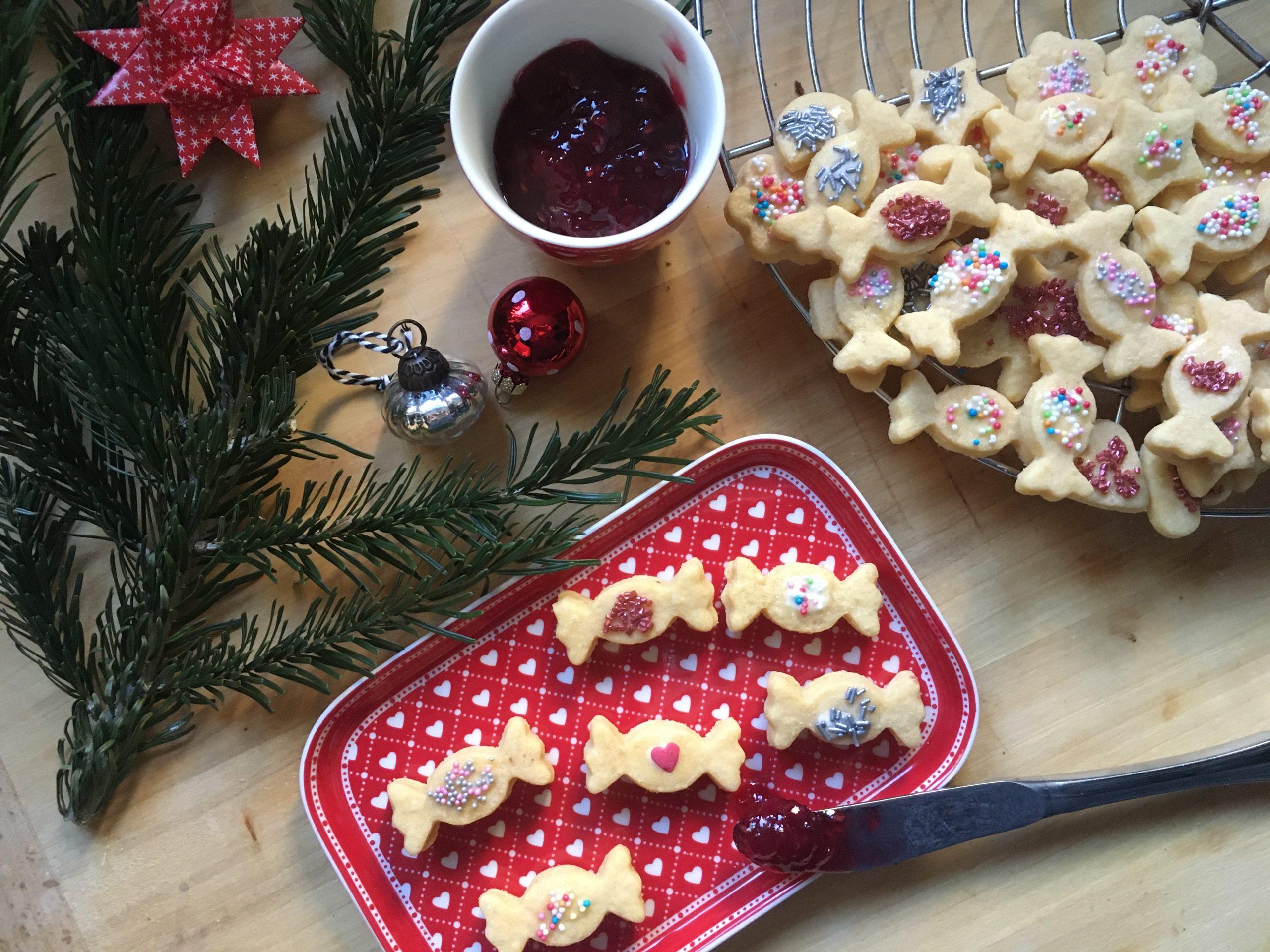 Plätzchen in Bonbonform mit weihnachtlicher Deko auf Tablett angerichtet